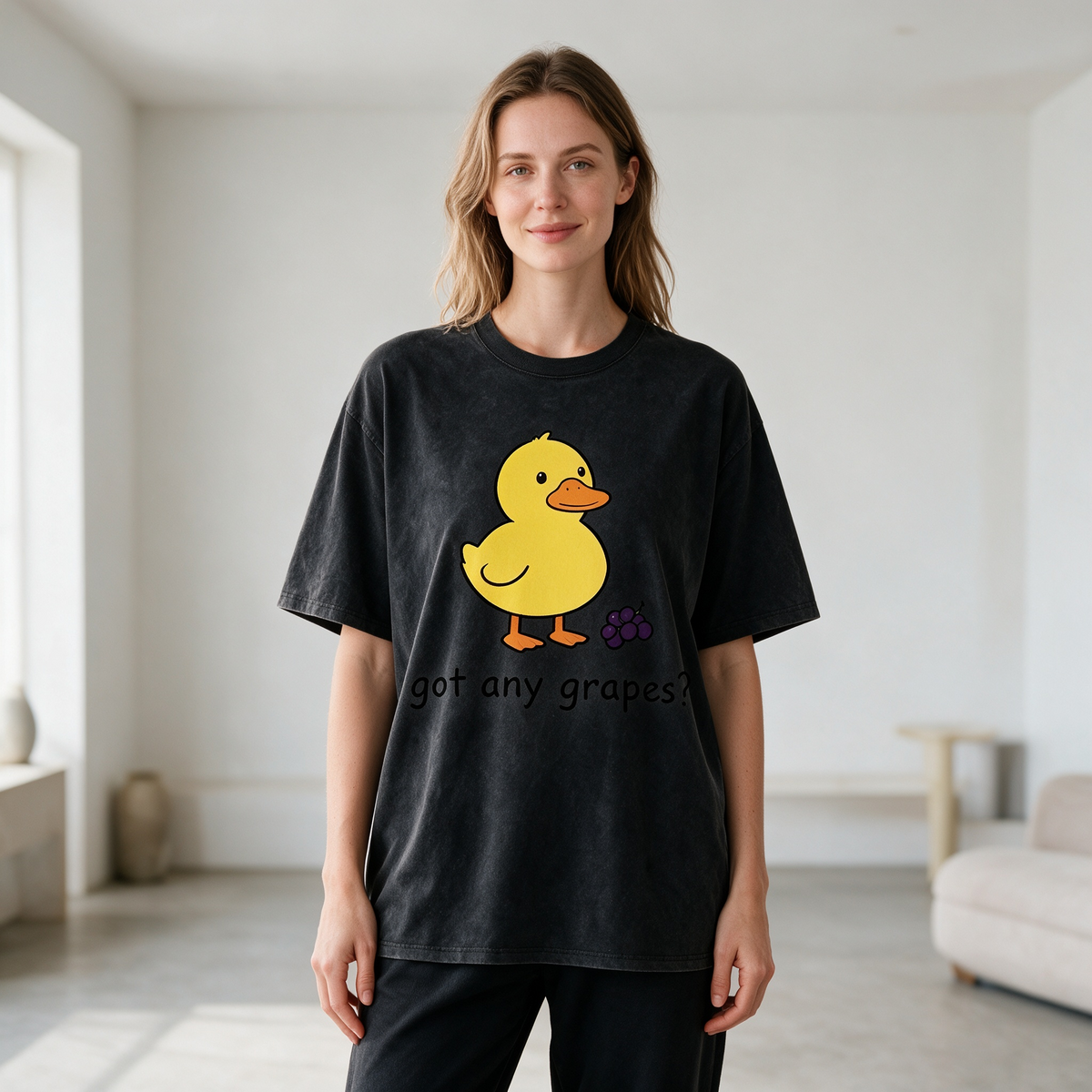 Vintage-style washed cotton T-shirt for women; features a cute graphic of a little yellow duck with grapes and playful English text; designed with a relaxed, drop-shoulder fit and short sleeves.